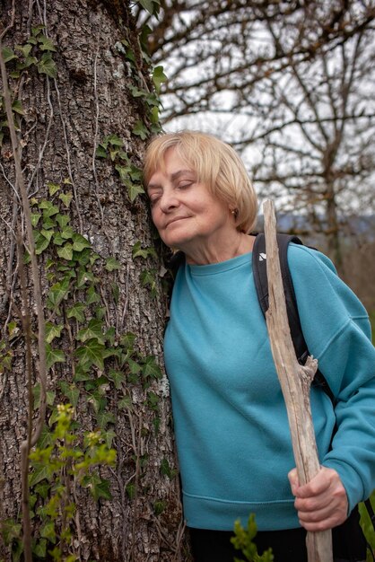 Photo une vieille dame se repose contre un arbre avec du lierre.