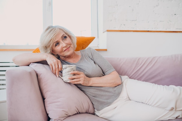 Vieille femme âgée caucasienne appréciant le thé de l'après-midi à la maison.