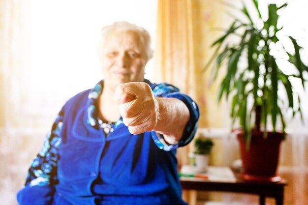 Une vieille femme âgée montre un geste de la main de figue