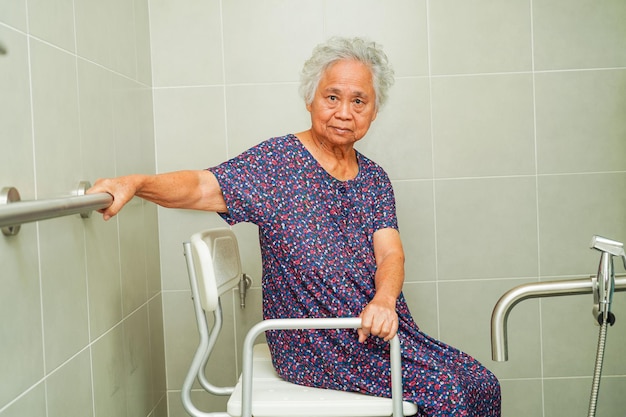 Une vieille femme asiatique âgée utilise un rail de support de toilette dans la barre d'appui de sécurité de la main courante de la salle de bain dans l'hôpital de soins infirmiers