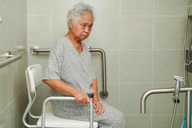 Une vieille femme asiatique utilise le rail de soutien des toilettes dans la rampe de sécurité de la salle de bain.