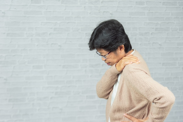 Vieille femme blessée à l'épaule sur gris