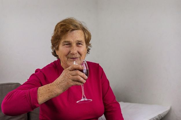 Une vieille femme boit du vin à la maison Mise au point sélective