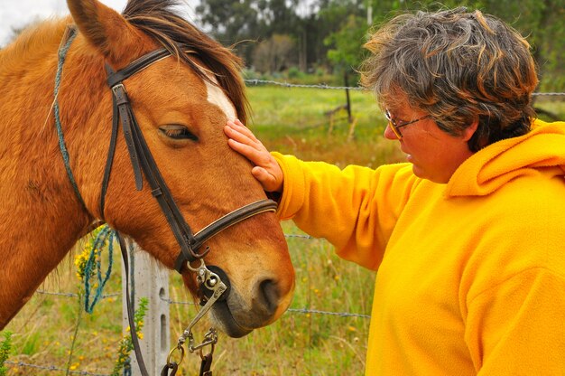 Vieille femme caressant avec son cheval