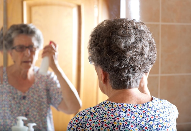 Une vieille femme entre 70 et 80 ans se peigne les cheveux devant