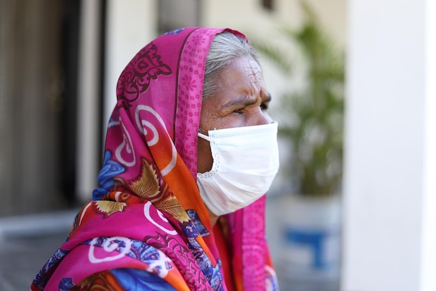 Vieille femme indienne assise à l'extérieur de l'hôpital portant un masque facial avant de passer un test covid-19