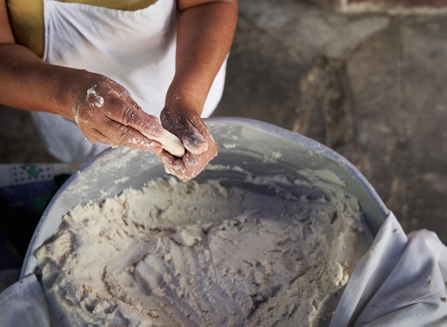 Une vieille femme méconnaissable prépare des tortillas de maïs à la main sur une grille dans sa modeste cuisine de rue.