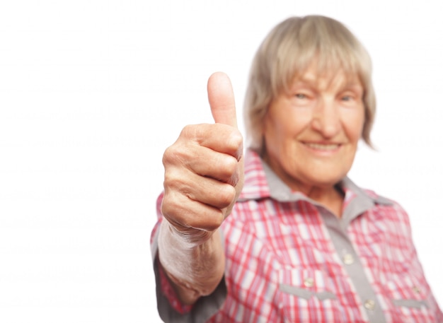 Vieille femme montrant signe ok sur un mur blanc