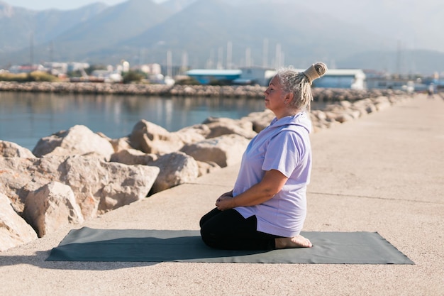 Vieille femme mûre avec des dreadlocks pratiquant le yoga et le tai-chi en plein air au bord de la mer bien-être et bien-être