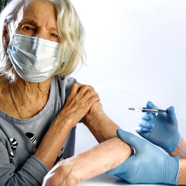 Photo une vieille femme reçoit le vaccin covid-19 d'un médecin.