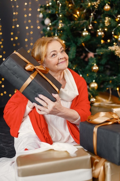 Vieille femme rousse s'asseyant près de l'arbre de Noël