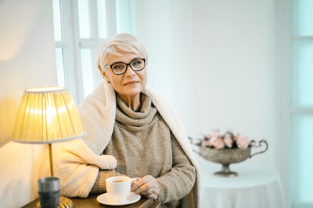 Vieille femme se détendre à la maison et boire du thé