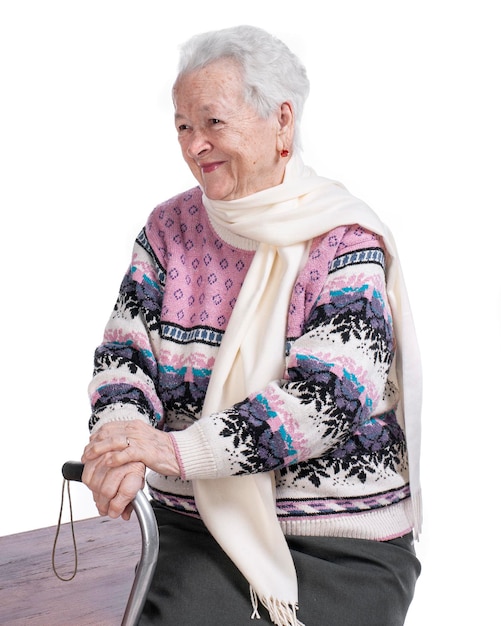 Vieille femme souriante avec une canne qui pose en studio sur fond blanc