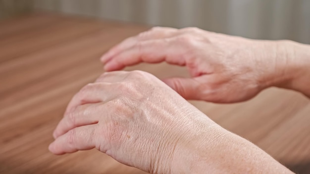 Vieille femme tremblant les mains ridées en raison de la maladie de parkinson