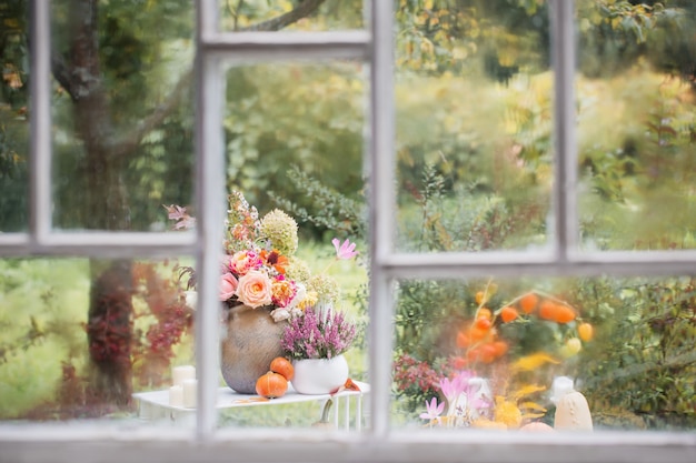 Vieille fenêtre en bois blanche avec des gouttes de pluie et décor d'automne dans le jardin