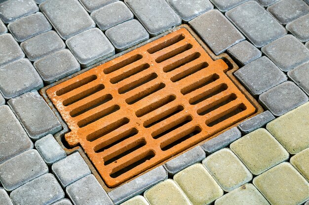 Vieille gouttière en métal rouillé pour l'eau de pluie sur le trottoir pavé