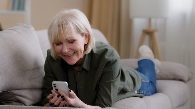 Vieille grand-mère caucasienne heureuse de 60 ans femme âgée de 50 ans dame blonde femme âgée se trouve sur le canapé