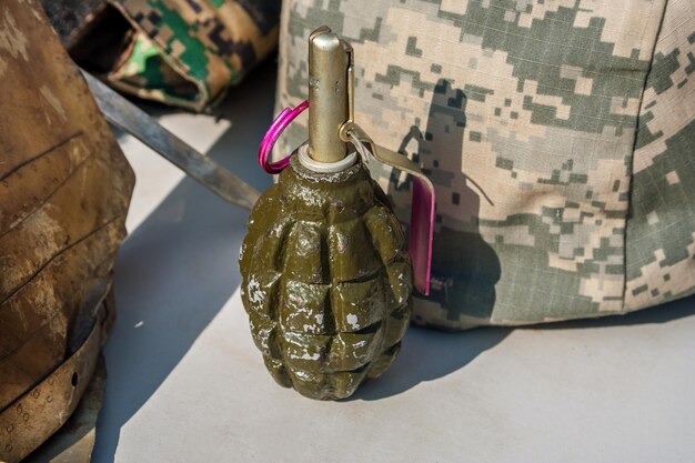 Vieille grenade à main soviétique F1 dans la perspective du camouflage et d'un casque