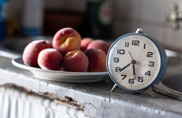 Vieille horloge bleue devant une assiette de prunes indiquant l&#39;heure d&#39;une collation