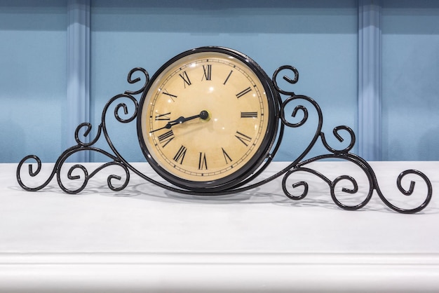 Photo vieille horloge vintage sur une étagère de cheminée dans un intérieur riche avec un chandelier