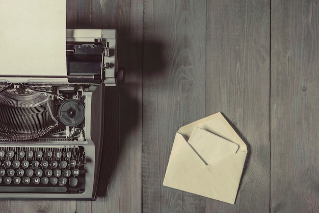 Photo une vieille machine à écrire avec une feuille de papier et une enveloppe ouverte avec une lettre se trouvent sur une table en bois