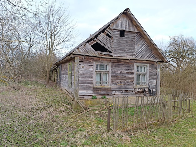 Une vieille maison en bois avec une clôture en arrière-plan