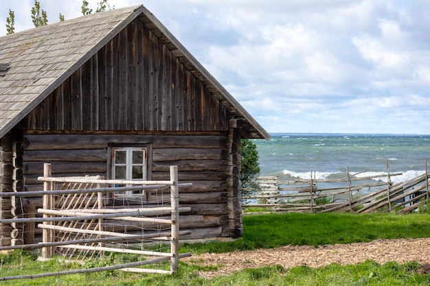 Une vieille maison en bois avec une clôture en bois au bord de la mer