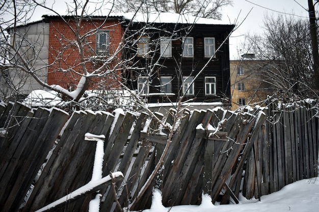 Vieille maison et clôture en bois en hiver