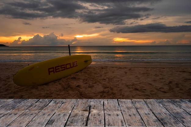 Vieille planche texturée contre Conseil de sauvetage jaune sur la plage au crépuscule