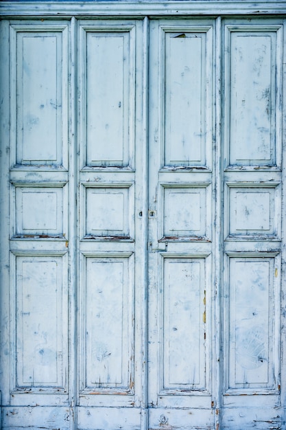 Vieille porte en bois de couleur bleue avec des rectangles et des places découpés