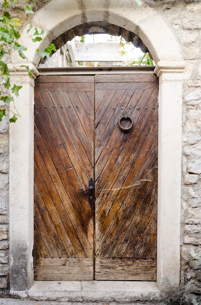 Vieille porte en bois, mur en pierre voûté. Gros plan de style rustique et rétro.