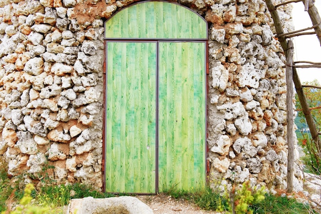 Vieille porte en bois verte avec mur de pierre