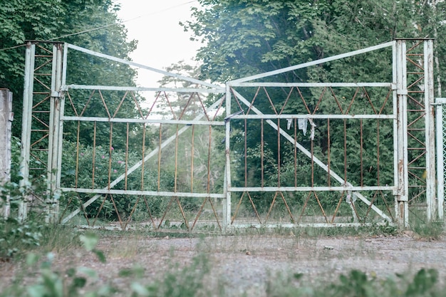 Vieille porte métallique abandonnée, sur la route forestière herbeuse