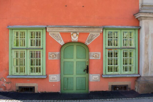 Vieille porte verte ronde et deux fenêtres sur la façade de couleur orange Gdansk Pologne