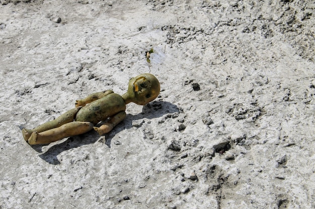 Vieille poupée cassée abandonnée sur un sol en béton gris