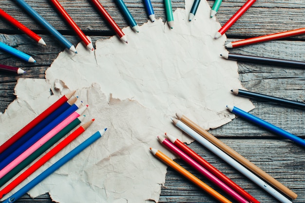 Sur une vieille table en bois, une vieille feuille, du parchemin joliment disposé à côté des crayons