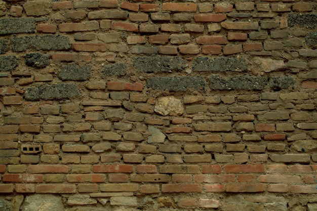 Vieille texture de mur de brique irrégulière patiné avec des rangées de briques apparentes de tailles et de formes variées