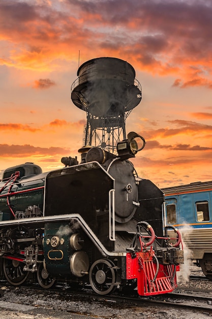 Photo la vieille vieille locomotive à vapeur sur fond de coucher de soleil.