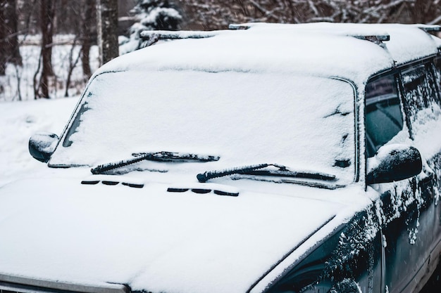 Vieille voiture couverte de neige, conduite par temps de neige