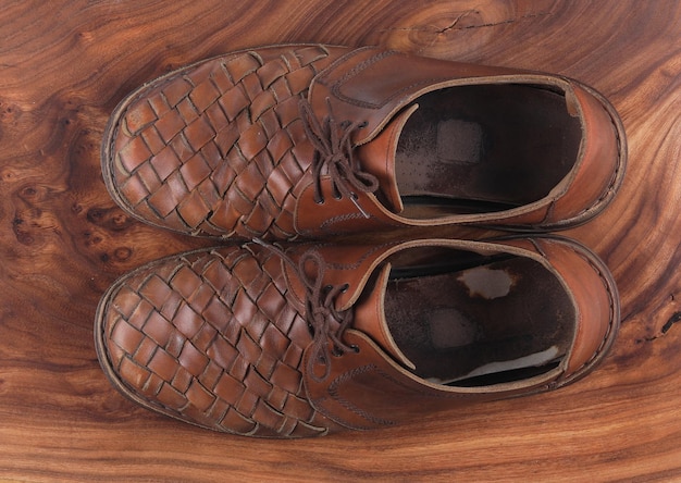 Vieilles chaussures en cuir marron sur fond de bois