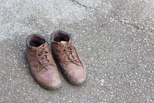 Vieilles chaussures en cuir marron sur sol en ciment