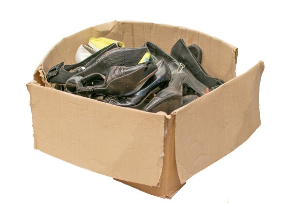 Vieilles chaussures jetées dans une boîte en carton isolée sur fond blanc
