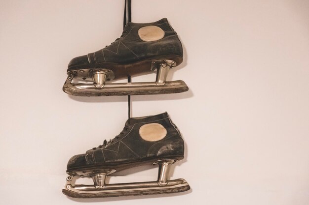 Photo de vieilles chaussures de patinage sur glace sont attachées au mur sur un clou.