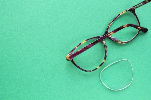 Photo vieilles lunettes cassées avec lentille endommagée sur fond vert mauvaise vue concept de réutilisation et de réparation