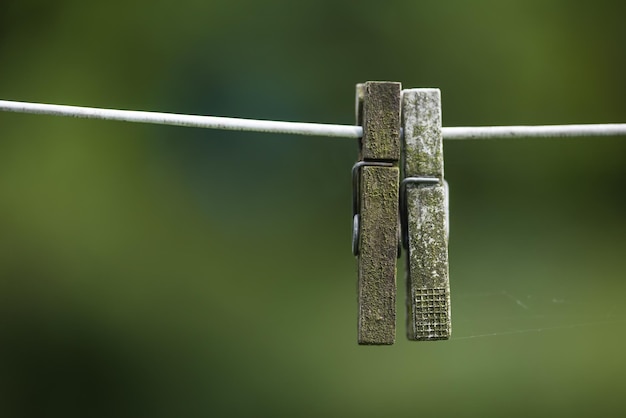 Vieilles pinces à linge sur une corde à linge à l'extérieur sur un arrière-plan flou avec espace de copie Détails de deux pinces à linge en bois patiné utilisées comme objets ménagers pour accrocher et sécher les vêtements le jour de la lessive