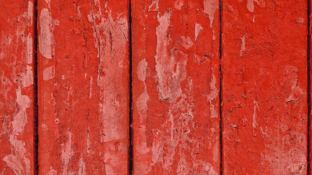 Vieilles planches en bois avec peinture écaillée rouge avec des fissures.