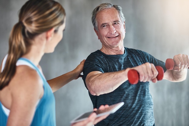 Vieillir devenir plus en forme devenir plus fort Photo d'un homme âgé utilisant des poids avec l'aide d'un physiothérapeute