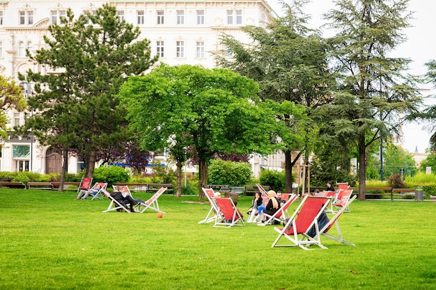 Vienne, Autriche - 19 Mai 2019 : Jeunes Assis Sur Des Transats Sur L'herbe Dans Le Parc Sigmund Freud Dans Le Vieux Centre-ville De Vienne En Autriche. Pelouse Verte Et Arbres à Wien. Voyages Et Tourisme Au Printemps