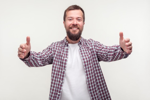 Viens dans mes bras Portrait d'un homme barbu heureux et débonnaire en chemise à carreaux levant les mains pour un câlin et souriant amicalement à la caméra expression hospitalière tourné en studio intérieur fond blanc