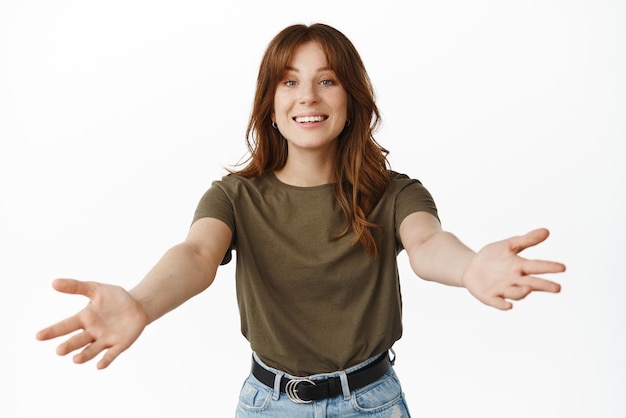 Viens ici Belle femme souriante vous invitant et vous accueillant étendez les mains sur le côté pour serrer dans ses bras quelqu'un debout sur fond blanc